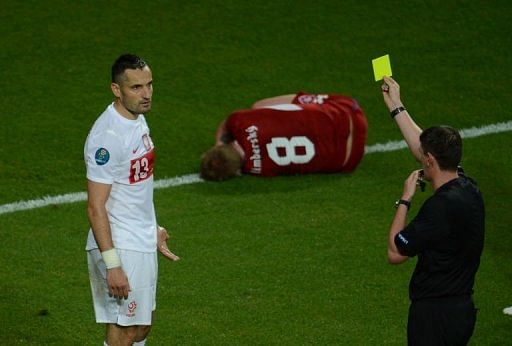 Polish defender Marcin Wasilewski (L) is given a yellow card